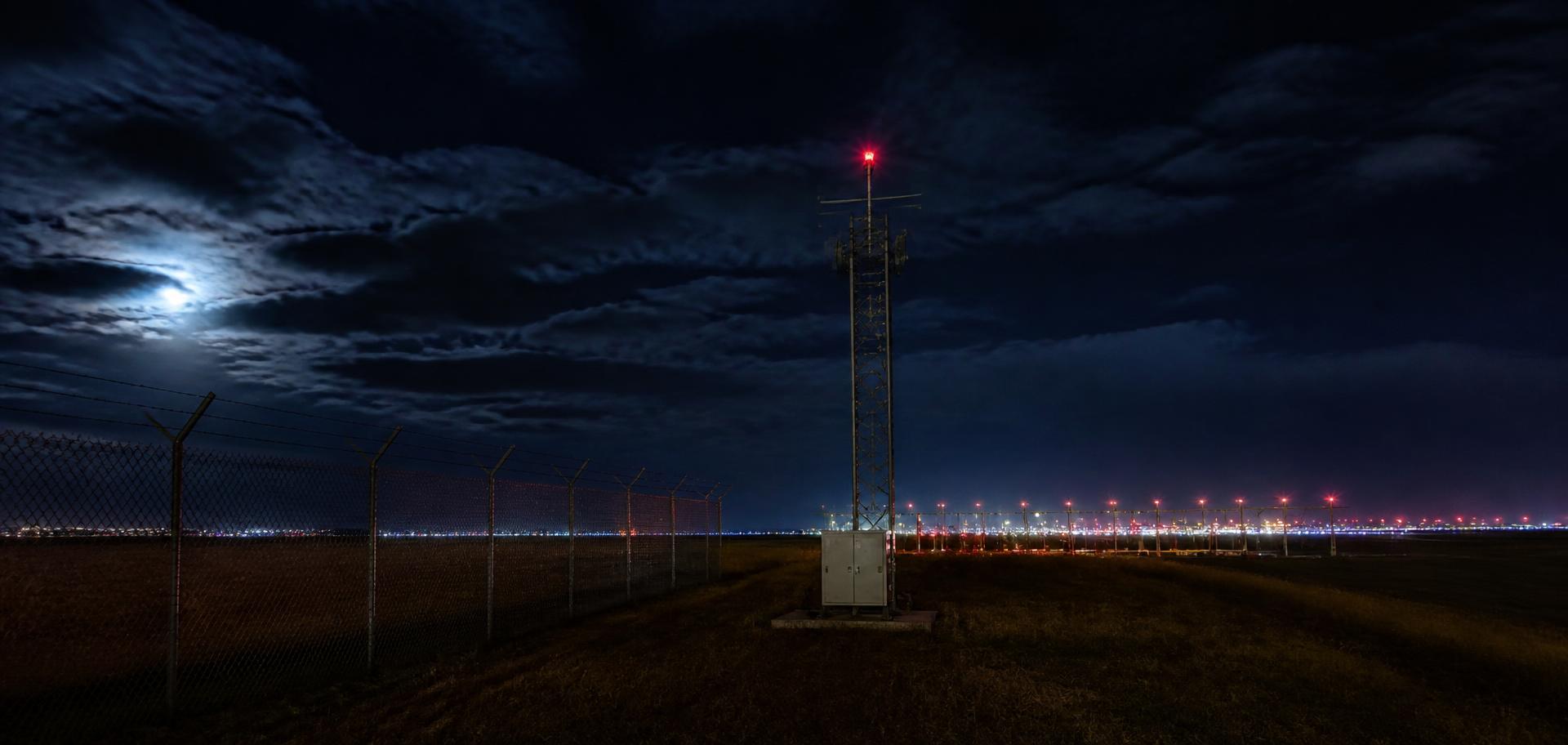 Sensor mast on an airport perimeter under a night sky